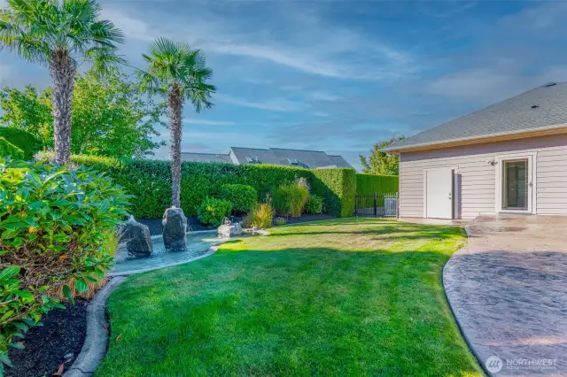Outdoor living at its best—relax in the private hot tub, unwind beside the soothing water feature, or entertain on the stamped concrete patio. Manicured landscaping with tropical accents and custom curbing make this backyard both stunning and low-maintenance.