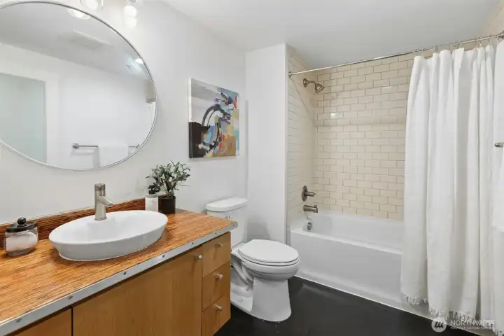 A full bath, with marmoleum flooring and wood laminated vanity top