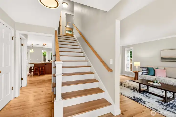 A bright entry opens to updated hardwoods and a beautifully finished staircase, featuring newer posts, rail, and banisters, plus crisp solid wood trim and baseboards throughout.
