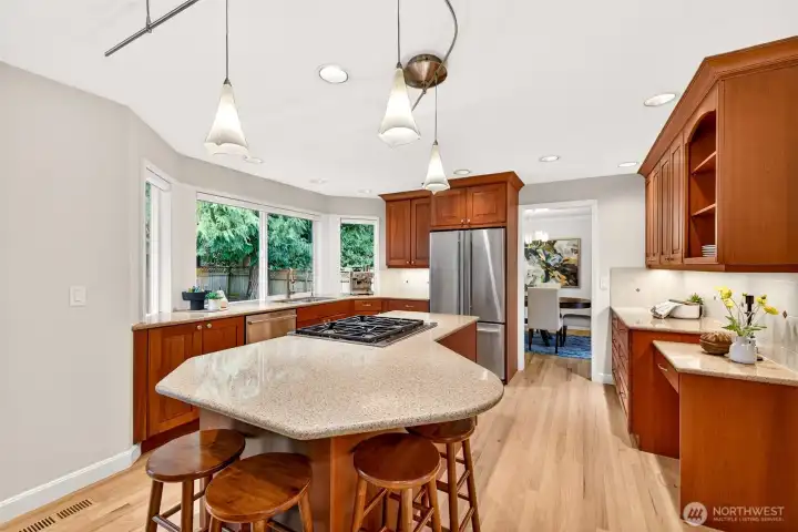 A large entertaining island anchors the space with plenty of room for gatherings, complemented by stainless appliances, stone surfaces, and recessed lighting that keeps the kitchen bright and welcoming.