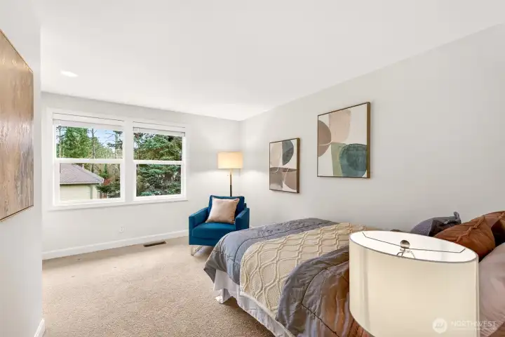 Large windows invite soft natural light and greenery views, creating a flexible bedroom space that can adapt as needs change over time.