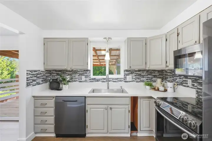 A window over the sink overlooks the covered deck and backyard, bringing in natural light and creating a connection to the outdoor space.
