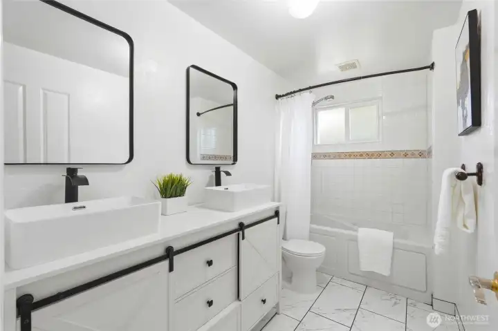 The main bathroom has been tastefully refreshed to reflect a more modern aesthetic. A new vanity provides both style and practical storage. The updated mirror enhances the space, adding a clean and polished look.