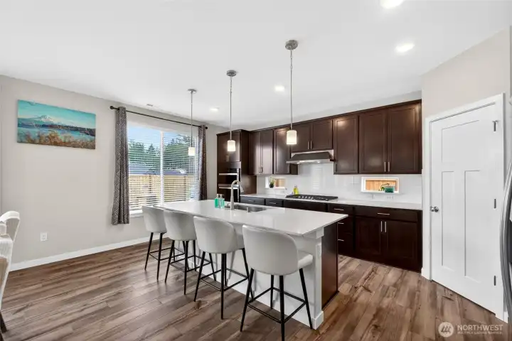 Chef's kitchen features a large center island, quartz countertops, cabinet lighting, built-in blue tooth speakers and a thoughtfully designed custom corner pantry