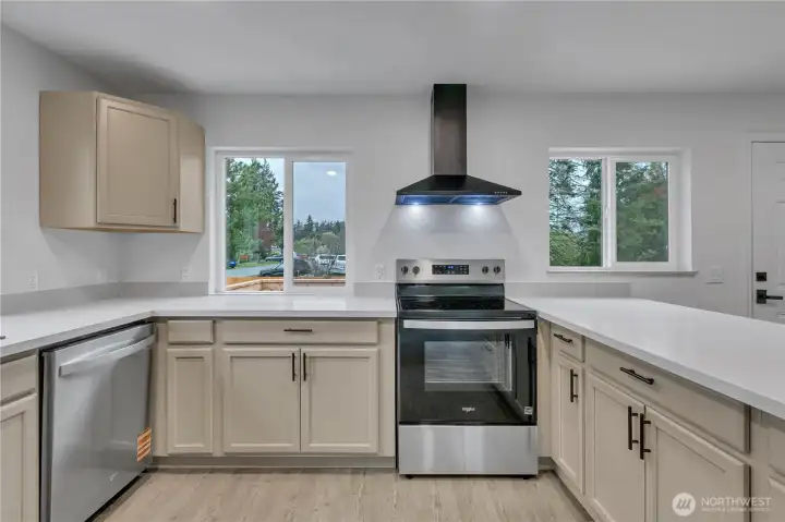 Bright kitchen featuring brand-new appliances, cabinetry, and modern countertops