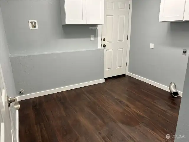 Large laundry room with upper cabinets. Space for refigerator and comes with water inlet to hook up ice maker. Door to backyard.