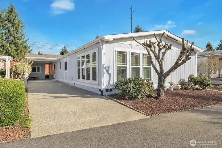 Street view of the home and the covered carport and parking area for 2 full sized vehicles. South facing windows and the West side windows all have blinds for privacy.