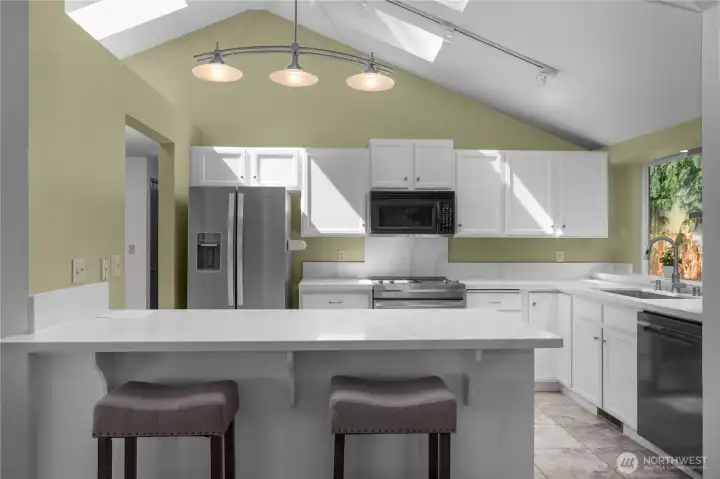 Bright kitchen features new counters and SS sink, fresh paint, SS Appliances, bar seating, and an efficient open layout.