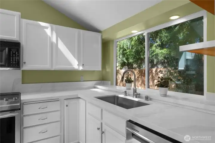 Large picture window and updated counters create a bright, cheerful kitchen workspace.