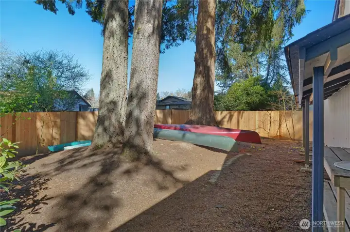 Private side yard area with mature trees and room for recreation or storage.