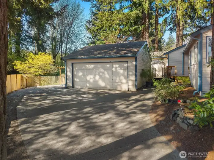 Spacious garage with additional paved parking for guests or extra vehicles.