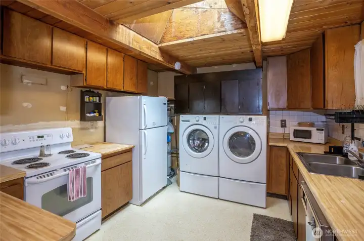 Kitchen area filled with natural light from the skylight, plus added cabinetry above the washer and dryer for extra storage and convenience. Kitchen area filled with natural light from the skylight, plus added cabinetry above the washer and dryer for extra storage and convenience.