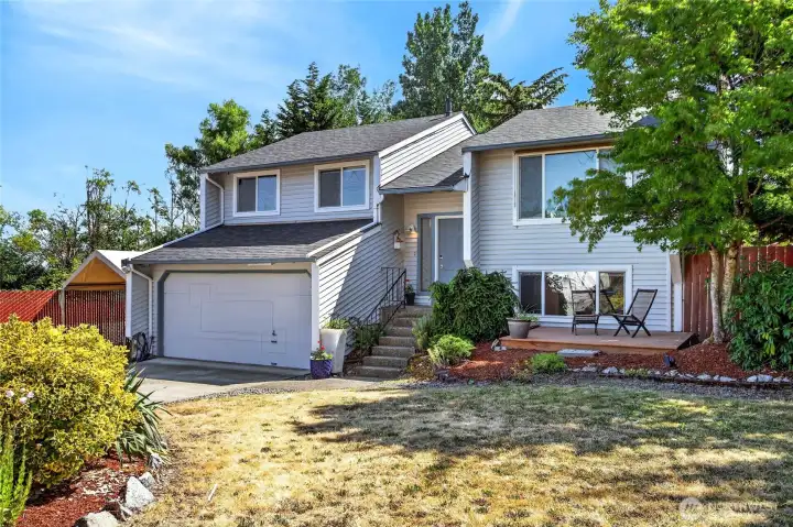 Another view of the home's exterior front, showing a quaint deck to relax in the shade.
