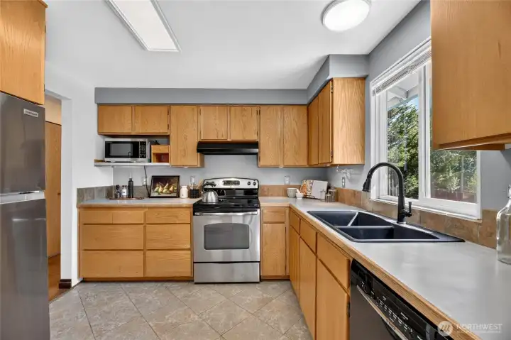The kitchen has warm, wood cabinetry with new SS refrigerator and microwave.   The large window provides a light-filled kitchen with a peaceful view into the backyard.