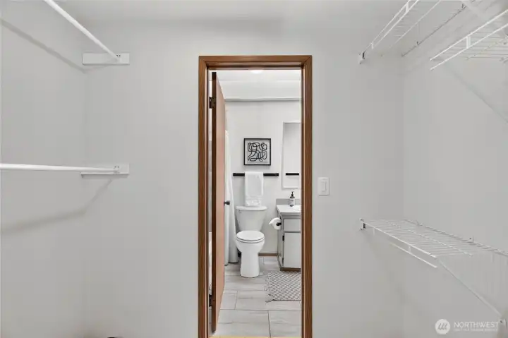 Primary bedroom walk-in closet and entrance into the bathroom.