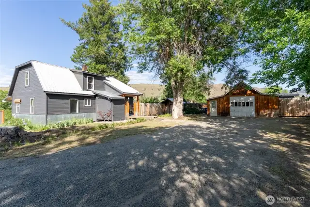 Mature trees guard the front entrance. Primary residence on left. Studio on right.