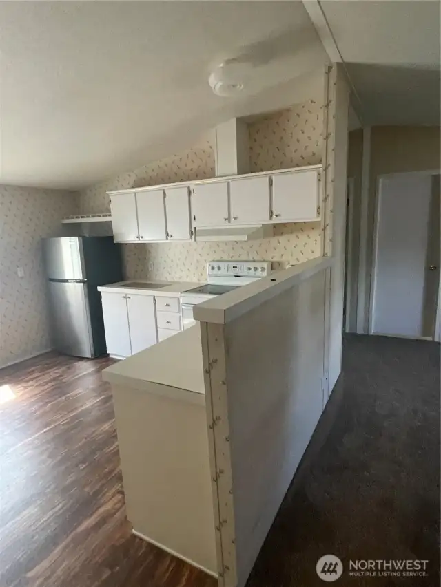Kitchen area with refrigerator and dishwasher and a space for smaller kitchen table.