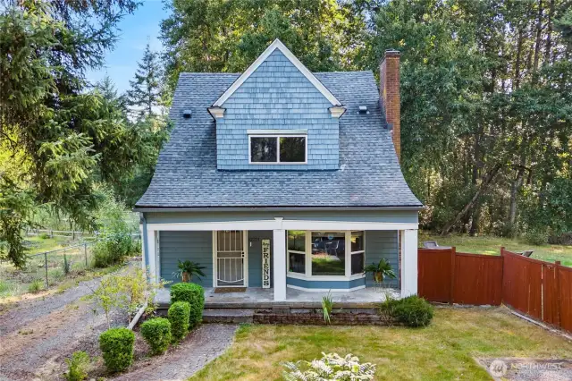 Overhead perspective showing the home’s charming roofline and surrounding evergreens, emphasizing its tucked-away setting among the trees.
