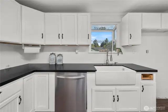 Close-up of the farmhouse sink and surrounding counter space, highlighting the kitchen’s balance of style and function with abundant storage and a bright window view.