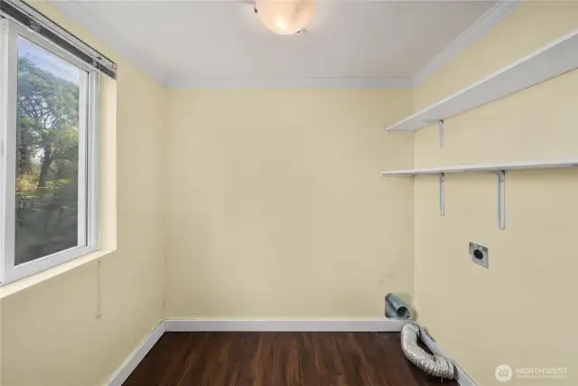 The laundry room is designed for efficiency, featuring washer and dryer hookups, shelving for supplies, and a window that brings in natural light. A rare and practical bonus, the laundry chute from upstairs delivers added convenience for handling daily tasks.