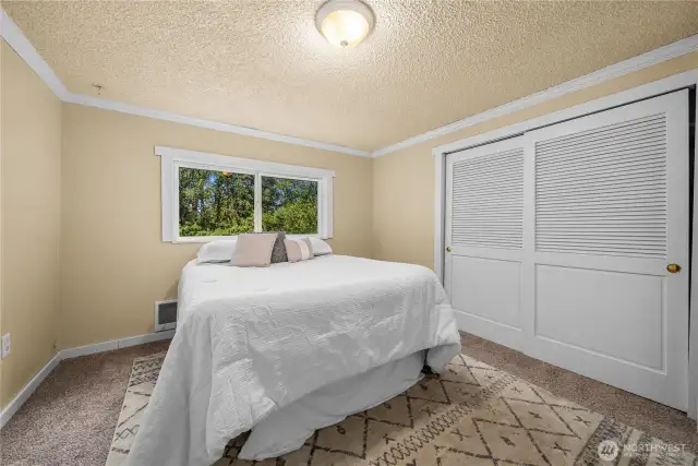 This spacious primary bedroom sits at the front of the home, featuring a large window that brings in natural light and overlooks the surrounding greenery. Ample closet space provides functionality while the cozy carpeting makes this a comfortable retreat.
