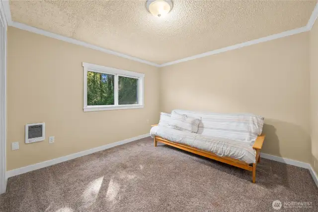 The third upstairs bedroom provides another comfortable space with a generous layout. With soft carpet underfoot and a window framing views of the outdoors, this room is both versatile and inviting.