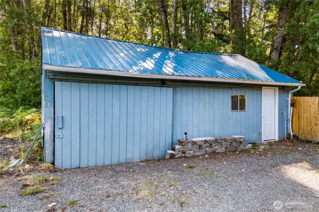 The detached garage offers excellent storage or workspace potential, set against a private treed backdrop for added seclusion. Its metal roof adds durability, making it a practical and lasting feature of the property.