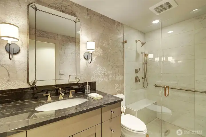 Hall bath that has beautiful designer  touches including walk in shower, sophisticated wall paper and special sink.