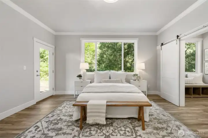 Main-level primary bedroom with private back porch and wooded views