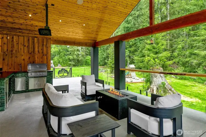 One of my favorite areas is the back patio; The tree of light gate leads to the backyard stairs. The built in kitchen is gorgeous, the green tile and black counters against the cedar are beautiful. Built in BBQ and counters with a little sink and a lot of space right by the window that goes to the dining area to make the space more inclusive for whoever is grilling! There are high quality heating and fans on back patio ceiling and the cedar roof with black lights is just beautiful. One of my favorite areas is the back patio; The tree of light gate leads to the backyard stairs. The built in kitchen is gorgeous, the green tile and black counters against the cedar are beautiful. Built in BBQ and counters with a little sink and a lot of space right by the window that goes to the dining area to make the space more inclusive for whoever is grilling! There are high quality heating and fans on back patio ceiling and the cedar roof with black lights is just beautiful.