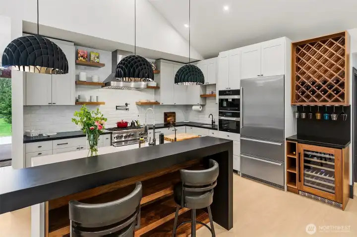 The kitchen has a mix of painted and walnut cabinets. The custom island features walnut cabinet with farm sink, waterfalls and Prado Bocci outlets, but the best features are the walnut shelving in the back and the intersected free standing black bar completely cladded in Cambria Matte Pool Black. The black pendant over the bar have been imported from Denmark. The kitchen has a mix of painted and walnut cabinets. The custom island features walnut cabinet with farm sink, waterfalls and Prado Bocci outlets, but the best features are the walnut shelving in the back and the intersected free standing black bar completely cladded in Cambria Matte Pool Black. The black pendant over the bar have been imported from Denmark.