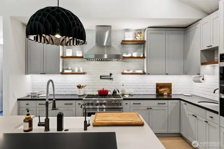 The kitchen has a mix of painted and walnut cabinets. The custom island features walnut cabinets with farm sink, waterfalls and Prado Bocci outlets, but the best features are the walnut shelving in the back and the intersected free standing black bar completely cladded in Cambria Matte Pool Black. The black pendant over the bar have been imported from Denmark. The kitchen has a mix of painted and walnut cabinets. The custom island features walnut cabinets with farm sink, waterfalls and Prado Bocci outlets, but the best features are the walnut shelving in the back and the intersected free standing black bar completely cladded in Cambria Matte Pool Black. The black pendant over the bar have been imported from Denmark.