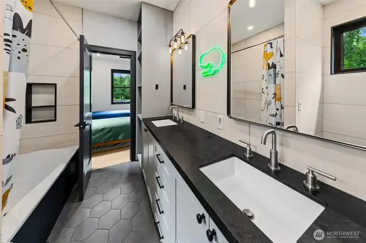 The shared bathroom is dramatic with a Caesarstone counter, Tub apron and niche, with large format tile installed at all wet areas (sink wall, tub walls, toilet walls... European style!). The floor is a fun charcoal hexagon tile, but what I like the most is the massive storage space in this bathroom with tall built ins flanking the double vanity. The shared bathroom is dramatic with a Caesarstone counter, Tub apron and niche, with large format tile installed at all wet areas (sink wall, tub walls, toilet walls... European style!). The floor is a fun charcoal hexagon tile, but what I like the most is the massive storage space in this bathroom with tall built ins flanking the double vanity.