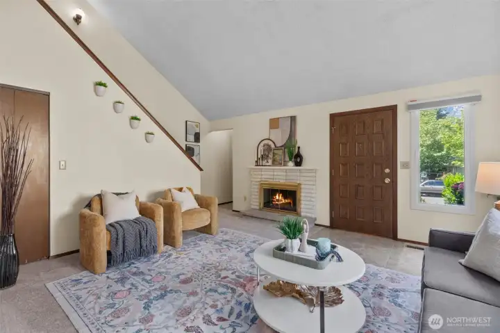 The airy living room with vaulted ceilings is anchored by a cozy fireplace, creating a warm and inviting feel The airy living room with vaulted ceilings is anchored by a cozy fireplace, creating a warm and inviting feel