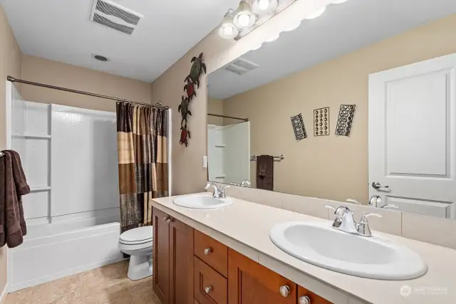 Hall full bathroom on the upper level accented with tile floor, two sinks and tile counter top.