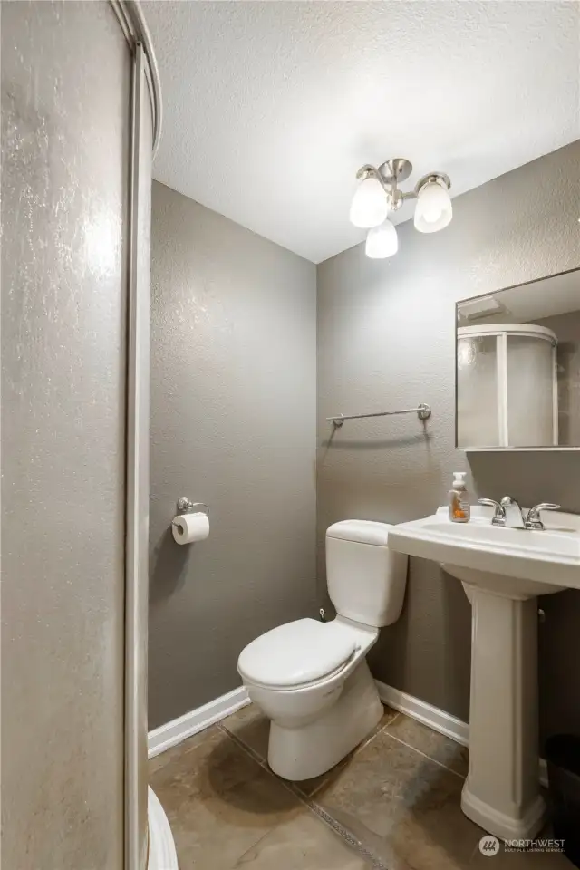 Bathroom with curved shower & pedestal sink.