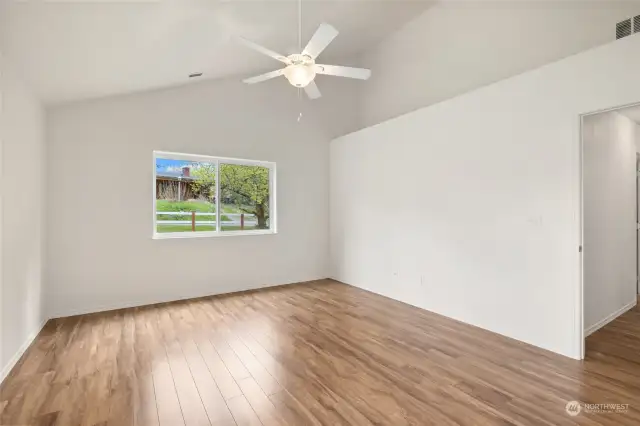 Primary bedroom with vaulted ceilings, ceiling fan and laminate floors