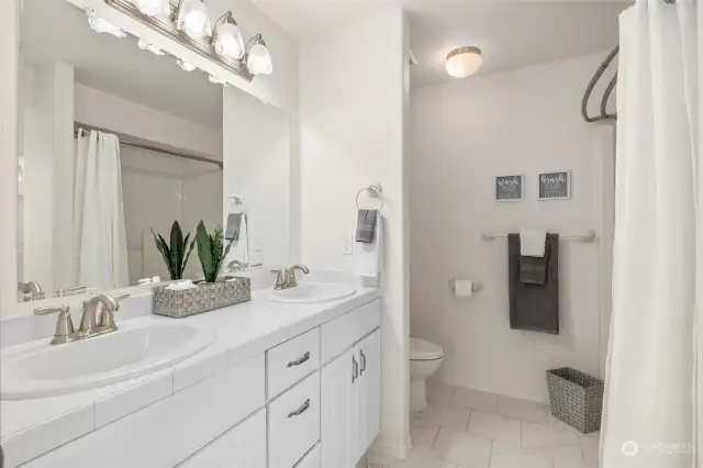 Primary bathroom with double sinks, tile counter tops, tile floor with a area for a vanity.