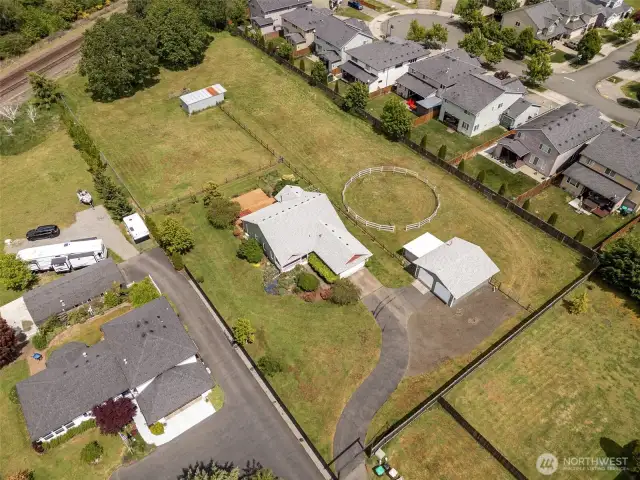 Space to roam! From this aerial view, spot the round pen perfect for your equine friends, the extra-long driveway tucked behind the manual gated entry, and all the room to live your best life.