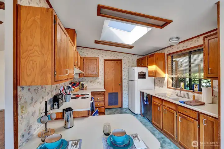 Galley style kitchen has plenty of prep and storage space. Oak Cabinets have open ledge area for additional cooking appliances , plants etc. Skylight brings in notable natual lighting all day.