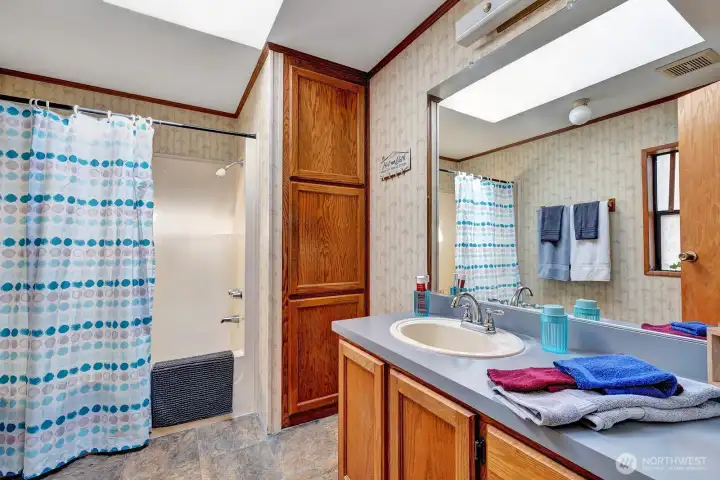 Primary bath has newer tub surround. Storage galore for all your bathing necessities.