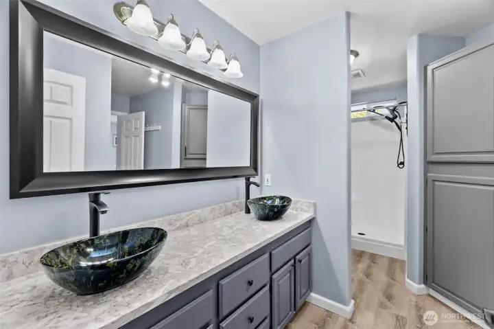 The primary bath with sparkling quartz counters, dual vanity vessel sinks, walk-in shower with new rainfal shower head, new toilet and fabulous storage!