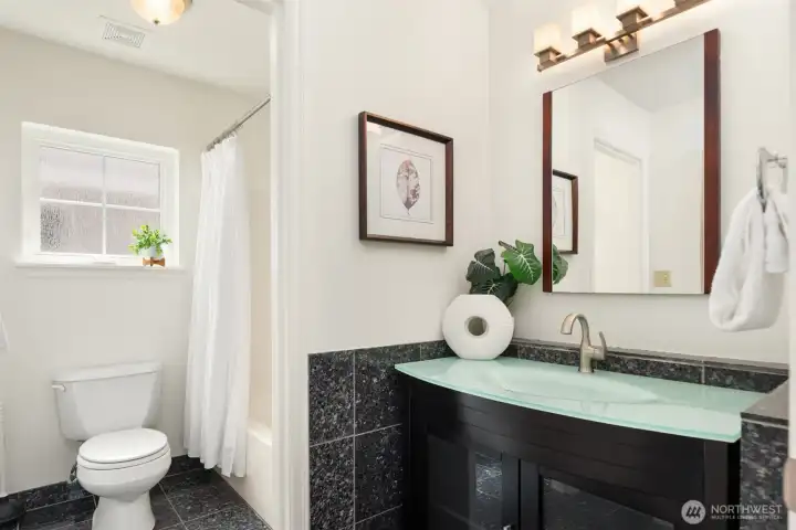 The main bath is large with a linen closet (unseen to the left) and a designer vanity as well as extensive tile work and a full bathtub.