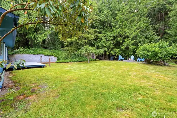 Spacious backyard featuring firepit, deck, garden shed and fenced storage surrounded by trees. Spacious backyard featuring firepit, deck, garden shed and fenced storage surrounded by trees.