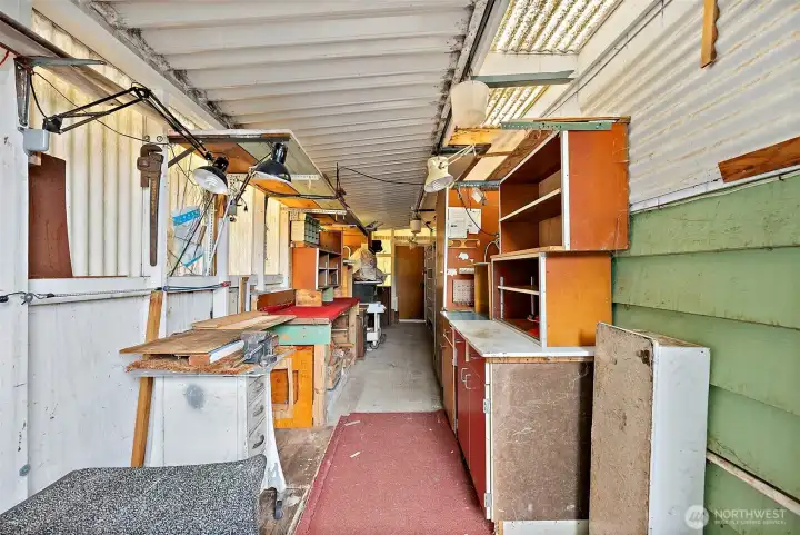 This functional shop in behind the carport. Lots of storage, lighting, and room to work & create projects.