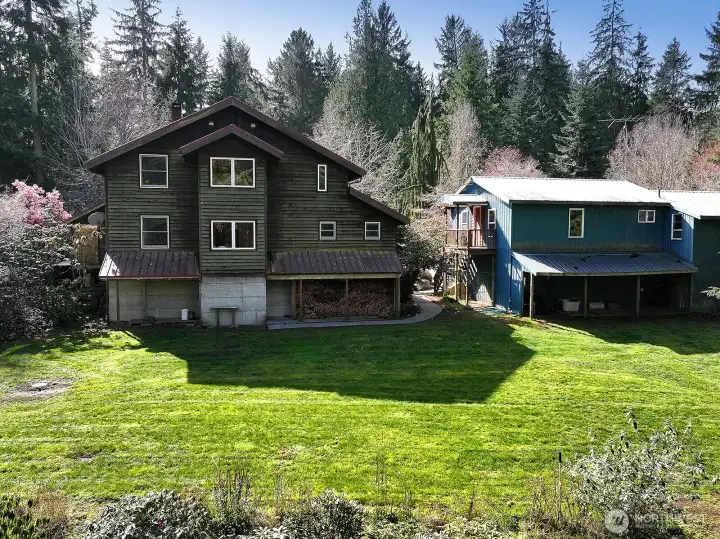 View of the back of the house, the ADU over the garage, and shops. The fenced in garden is below the house.