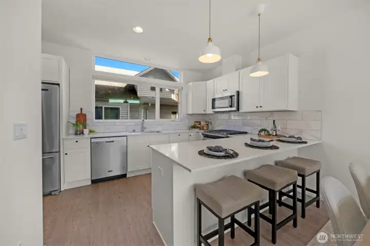 This modern kitchen features beautiful, crisp white cabinetry paired perfectly with high-end stainless steel appliances. The sleek, contemporary design is accented by soft-close cabinets and engineered hardwoods, creating a space that is as functional as it is stylish.