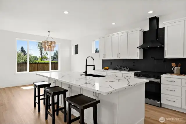 This stunning kitchen is the hub of the home. A massive island offers seating for informal dining. Sleek black accents play off of the detail in the quartz counters. Black tile back splash pull all of the details together.