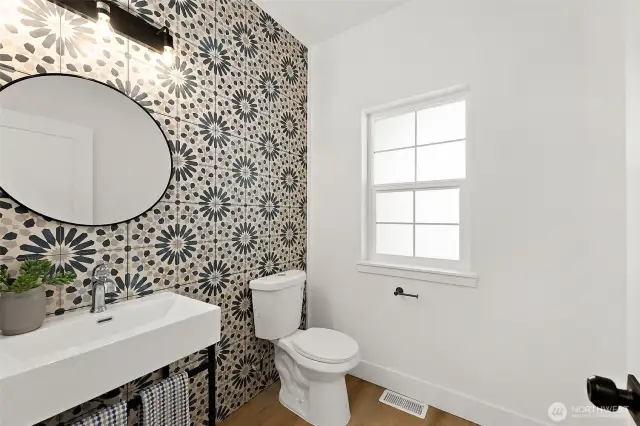 The powder room features a stunning tile accent wall and sleek pedestal sink.