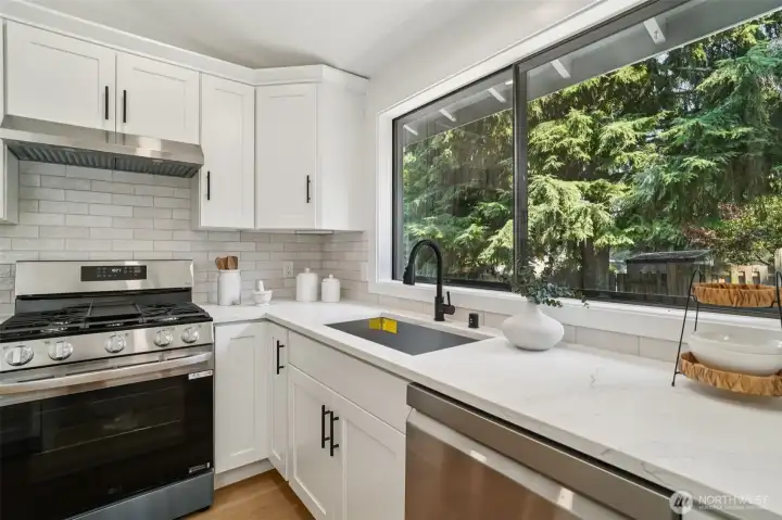 Big picture window bring the backyard green to the kitchen through the sink .